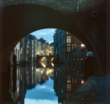 22122 Afbeelding van een doorkijk onder de boog van de Gaardbrug over de Oudegracht te Utrecht met op de achtergrond de ...